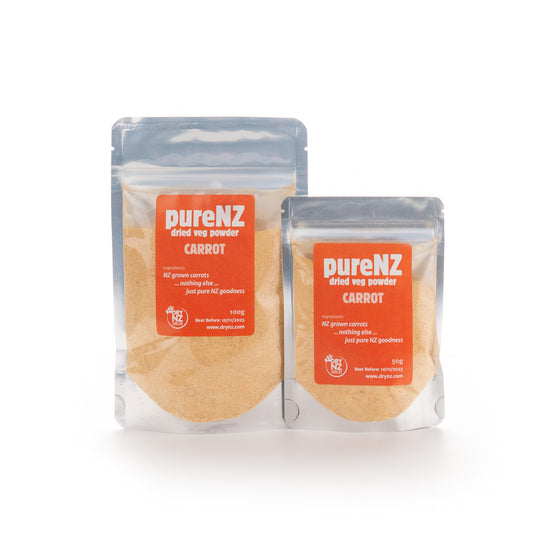 Two bags of PureNZ dried carrot powder, one larger and one smaller, with orange labels displaying the product name and weight.